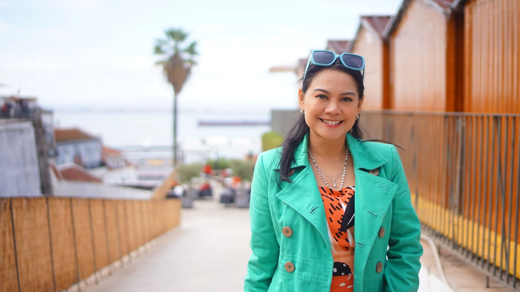 Nuniek Tirta Sari smiling on a sunny terrace above the harbour